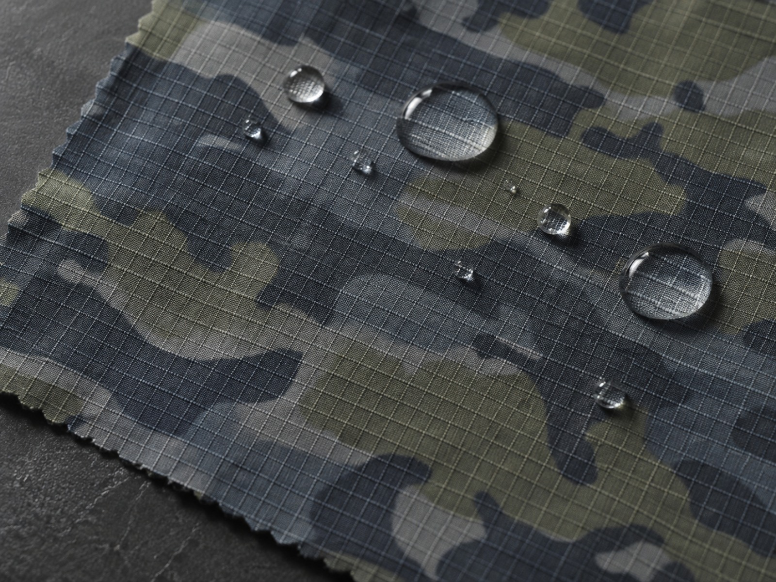 Macro view of waterproof fabric showing membrane layer and sealed seam construction on a tactical shell jacket